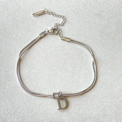 Elegant letter charm bracelets for women in gold and silver tones, featuring a delicate snake chain design and personalised letter charms.