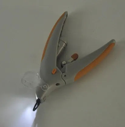 White plastic pet nail clipper with LED light on blister card packaging.