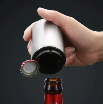 Stainless steel automatic bottle opener measuring 8.4 cm by 5.3 cm on a kitchen counter