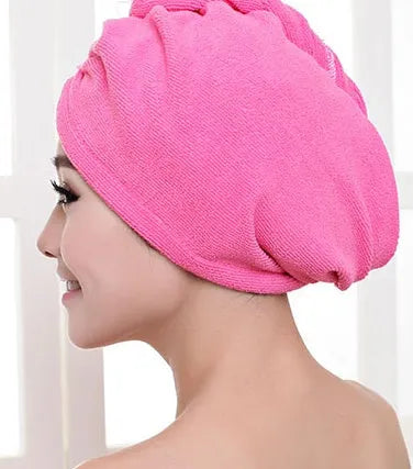 A woman wearing a sky blue microfiber hair dryer cap, with wet hair tucked inside, showing the towel's wrap-around design.
