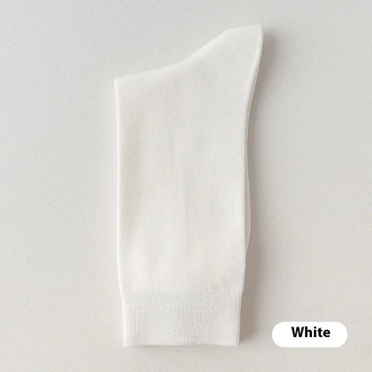 Pair of solid-colour men's mid-calf socks made from combed cotton on a wooden background
