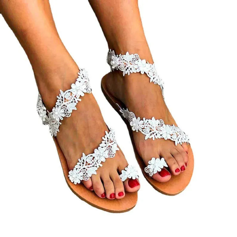 White casual flat sandals with rhinestone and floral decoration on a glossy PU upper.