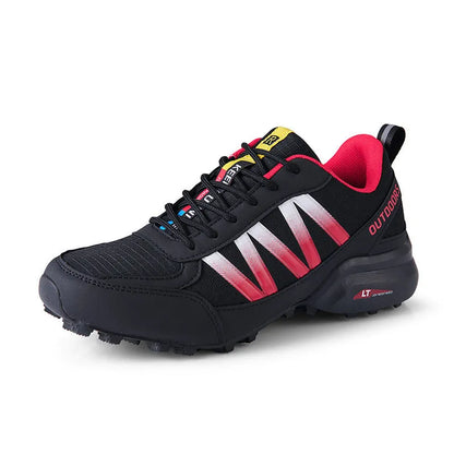 Men's black mountaineering sneakers with a rubber sole and lace-up front on a rocky surface.