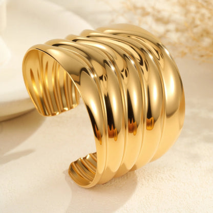 Women's stainless steel bracelet with 18K gold plating featuring exaggerated wide geometric wave design and niche opening