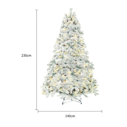 Green and white snow-dusted artificial Christmas tree on a metal stand, showing detailed PVC branches.