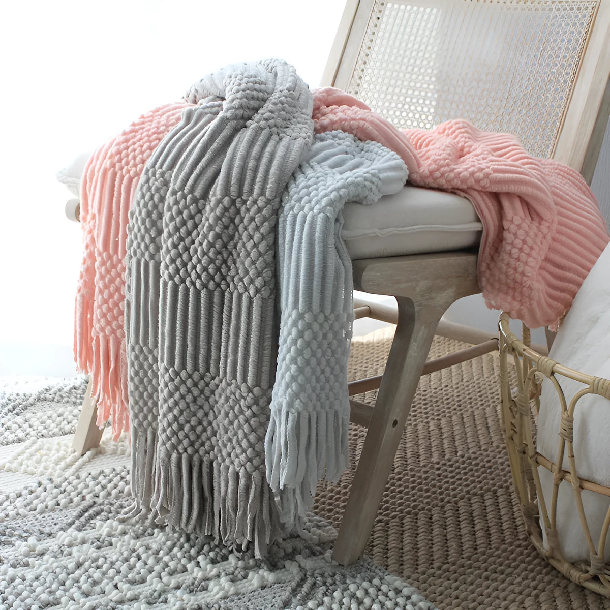 Nordic style knitted bubble texture blanket in light grey, draped over a sofa.
