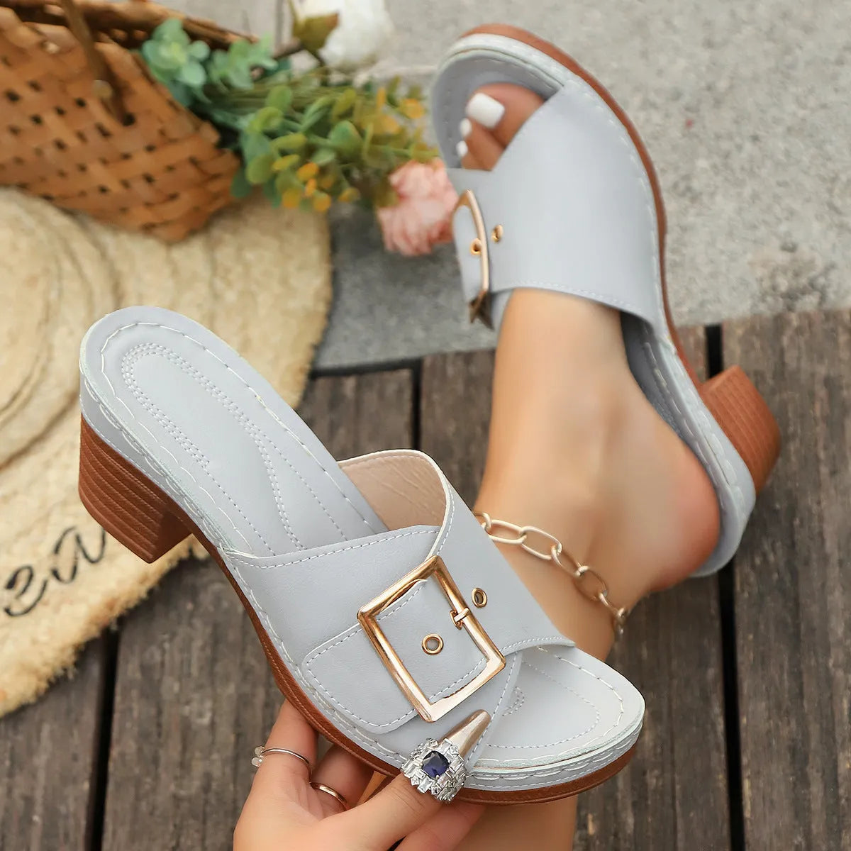 Women's black chunky heel slippers with a metal buckle and round toe, on a rubber sole