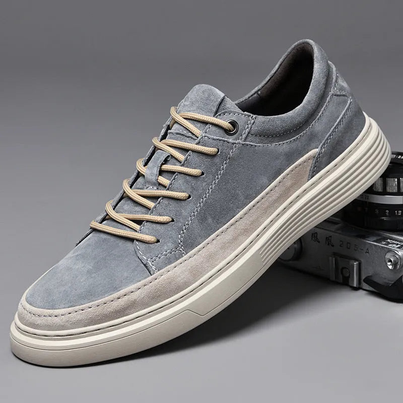 Men's grey low-top casual skate shoes with pigskin leather uppers and a flat rubber sole on a plain background.