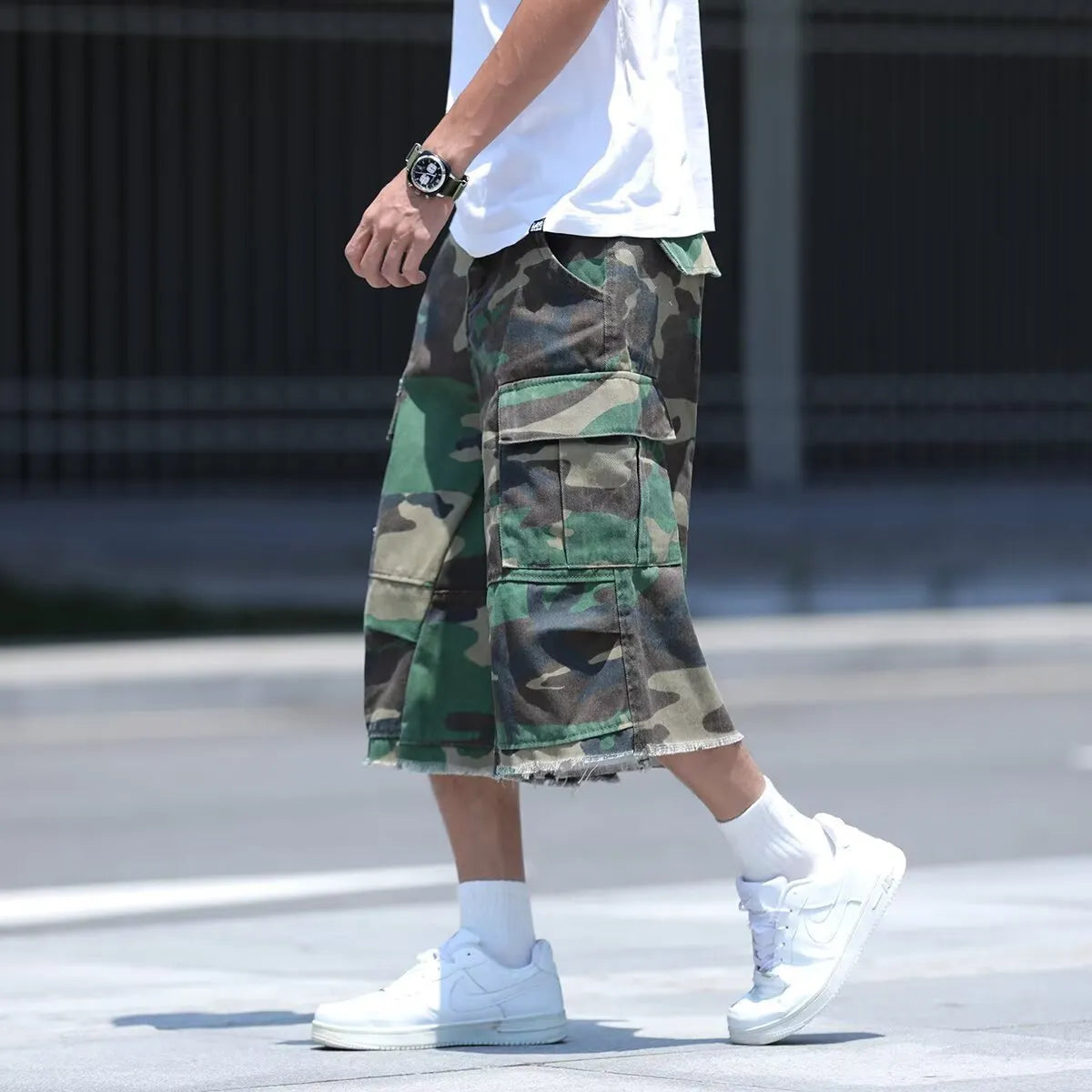 Man wearing loose-fit cropped camouflage shorts in a retro workwear style.