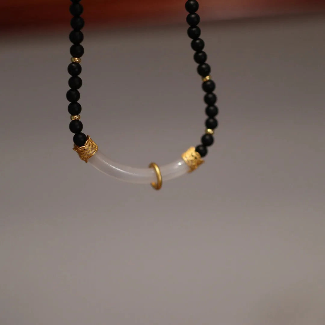 Close-up of a U-shaped necklace with frosted black agate, white chalcedony, and a 925 silver pendant on a beaded chain.