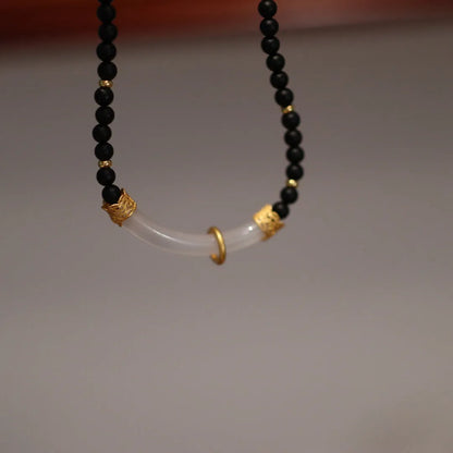 Close-up of a U-shaped necklace with frosted black agate, white chalcedony, and a 925 silver pendant on a beaded chain.