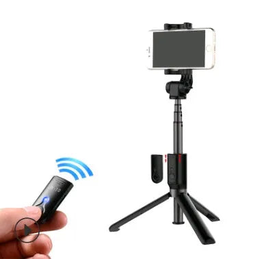Aluminium tripod selfie stick with extended phone clip and Bluetooth remote on a table
