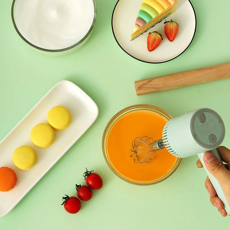 Green rechargeable electric hand mixer with whisk and beater attachments on a kitchen counter