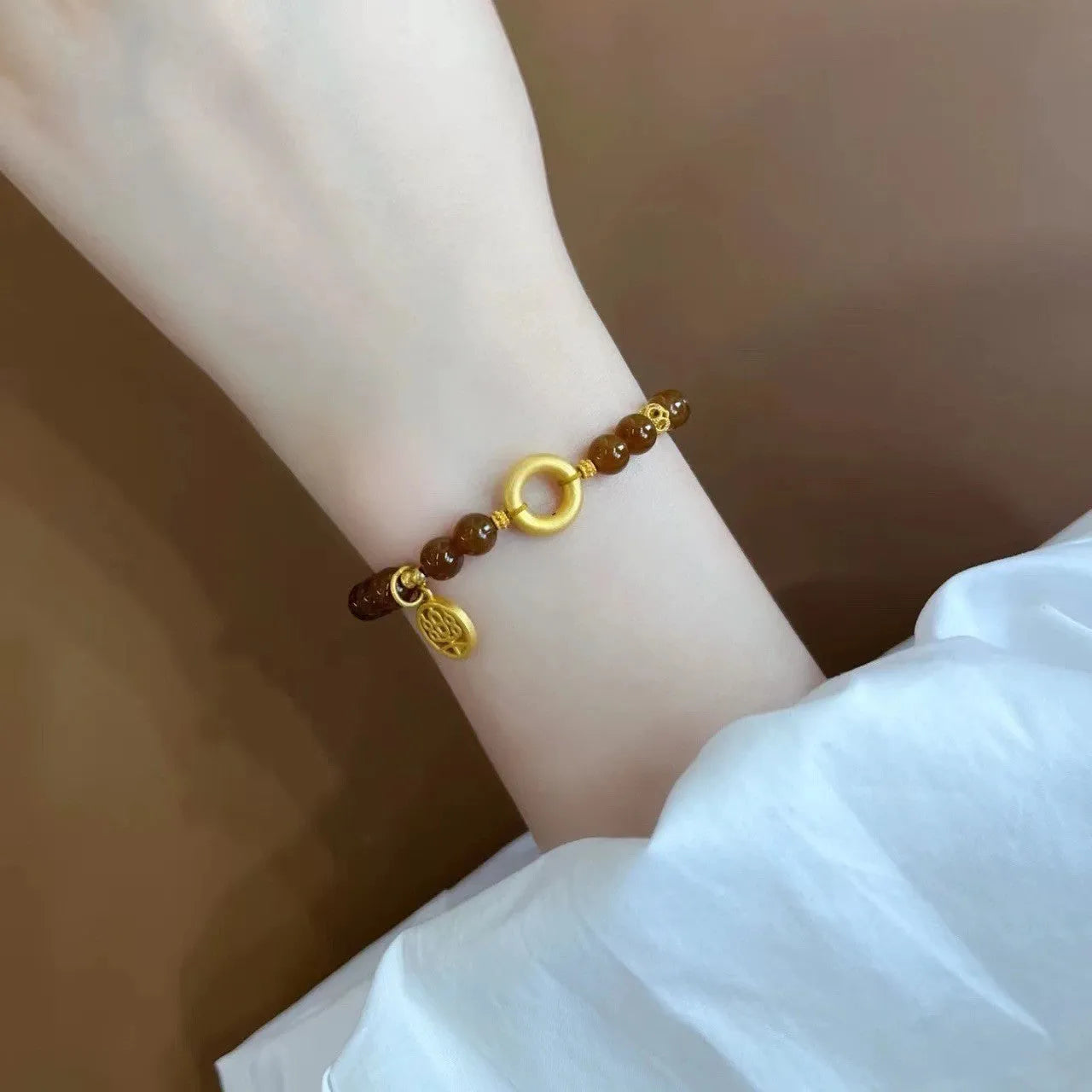 Caramel-coloured women's bracelet with beeswax Lily, music note, and blessing charms in New Chinese style.