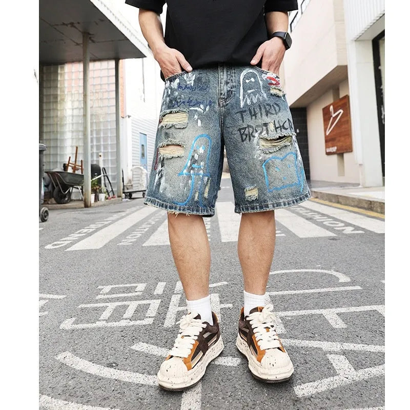 Blue men's jeans shorts with ripped distressed detailing and graffiti design, straight leg cut with zipper fly