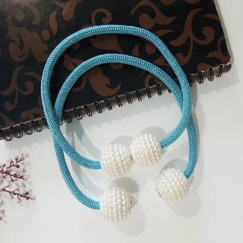 Magnetic curtain tiebacks with white pearl beads and fabric loops holding gathered curtain