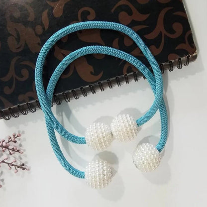 Magnetic curtain tiebacks with white pearl beads and fabric loops holding gathered curtain