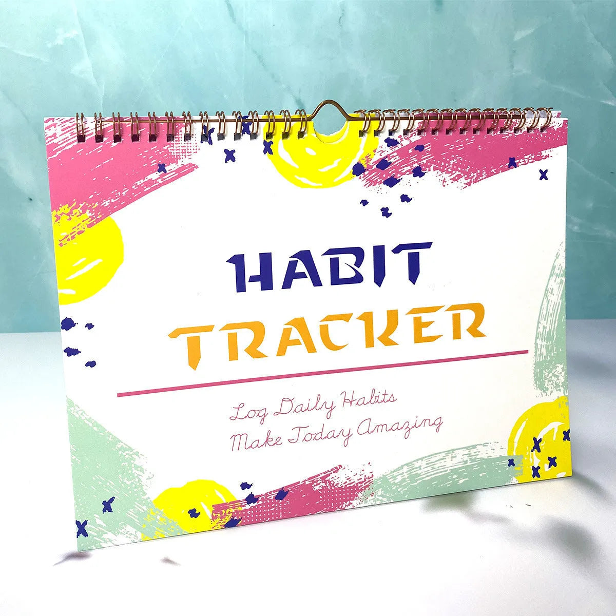 Habit tracking planner book open showing 12 internal pages, measuring 21cm by 28cm.