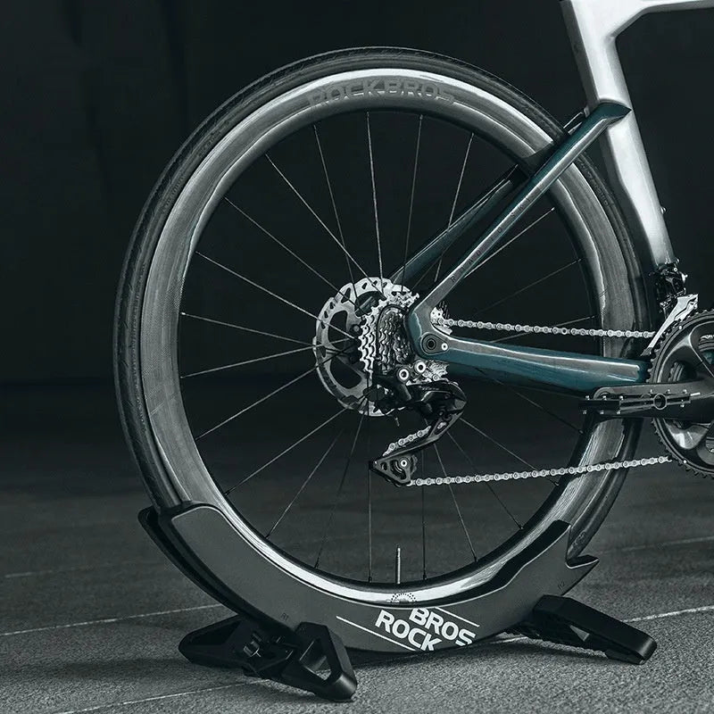 A black wall-mounted ABS plastic bracket holding a mountain bike vertically for storage.