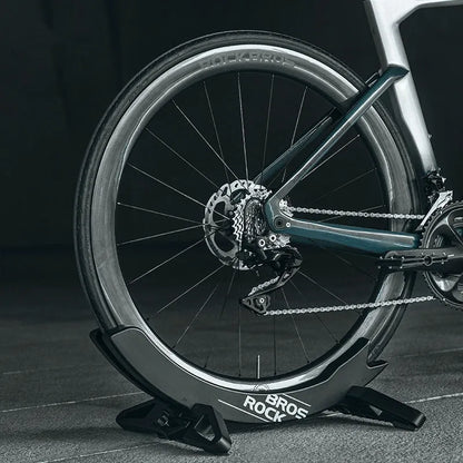 A black wall-mounted ABS plastic bracket holding a mountain bike vertically for storage.