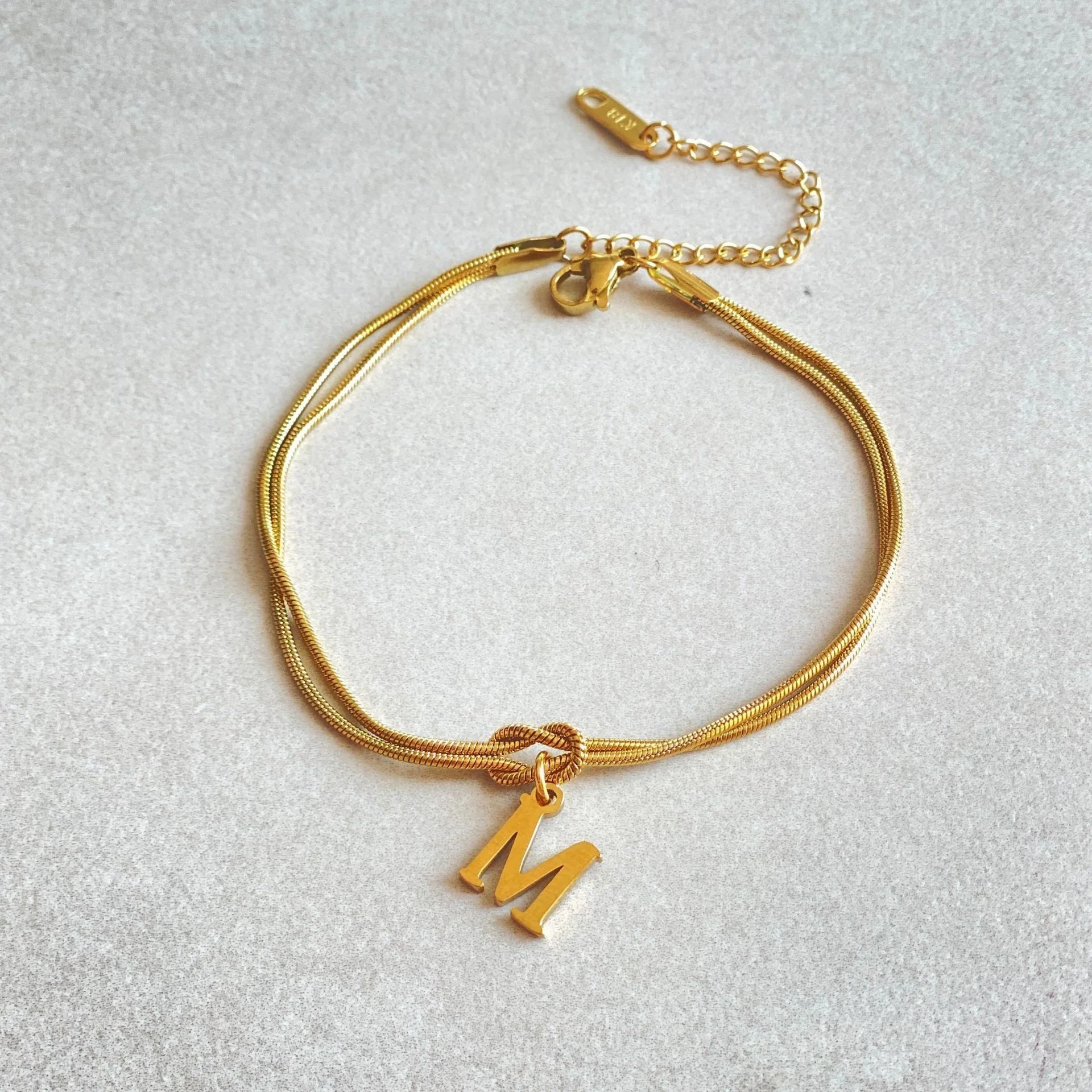 Elegant letter charm bracelets for women in gold and silver tones, featuring a delicate snake chain design and personalised letter charms.