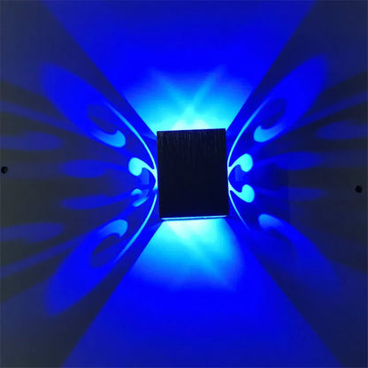 Modern aluminium butterfly-shaped LED wall lamp with colour-changing lights on a plain wall