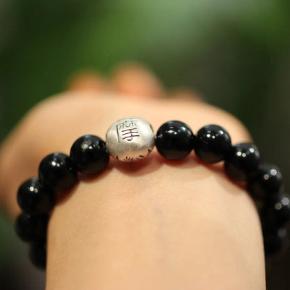 Close-up of a women's black agate bracelet with 10mm beads and a sterling silver clasp on a wrist.