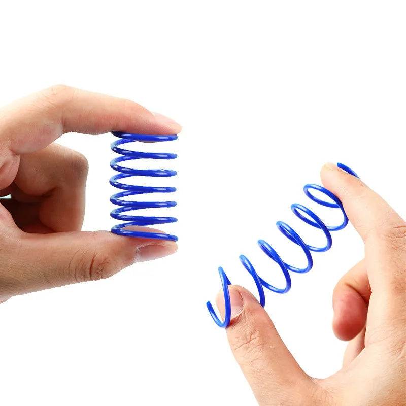 Assortment of colourful plastic coil spring toys for cats on a plain surface.
