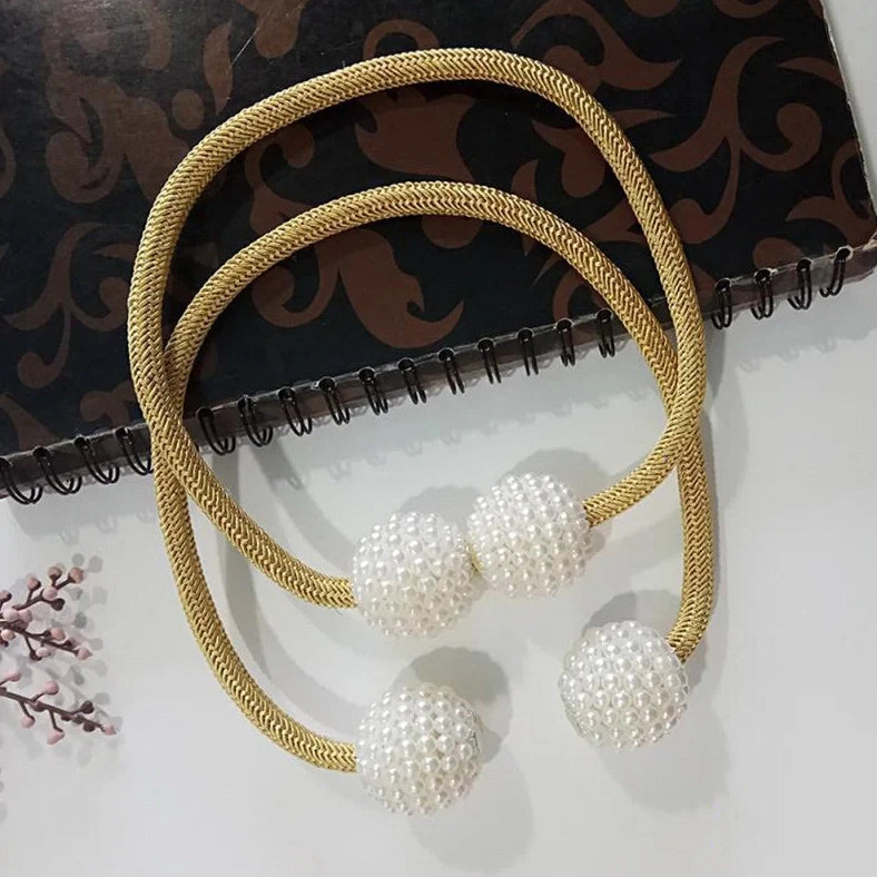 Magnetic curtain tiebacks with white pearl beads and fabric loops holding gathered curtain