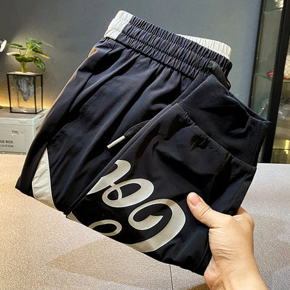 Black men's cropped casual trousers with ankle band made from thin ice silk cotton fabric.
