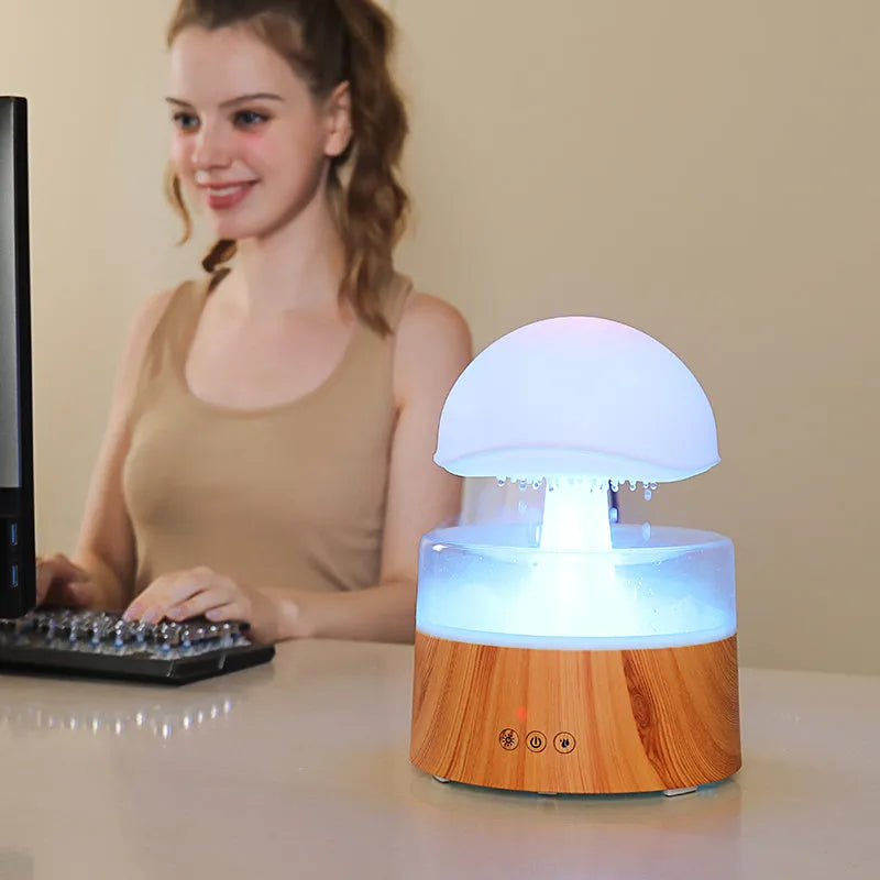 White cloud-shaped humidifier emitting mist with multicoloured LED light and water droplets