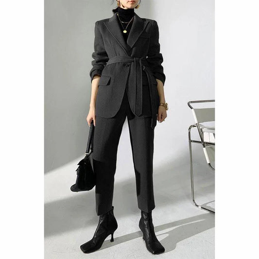 A chic and elegant woolen pant suit in black, featuring a belted jacket and warm trousers perfect for the autumn-winter season.