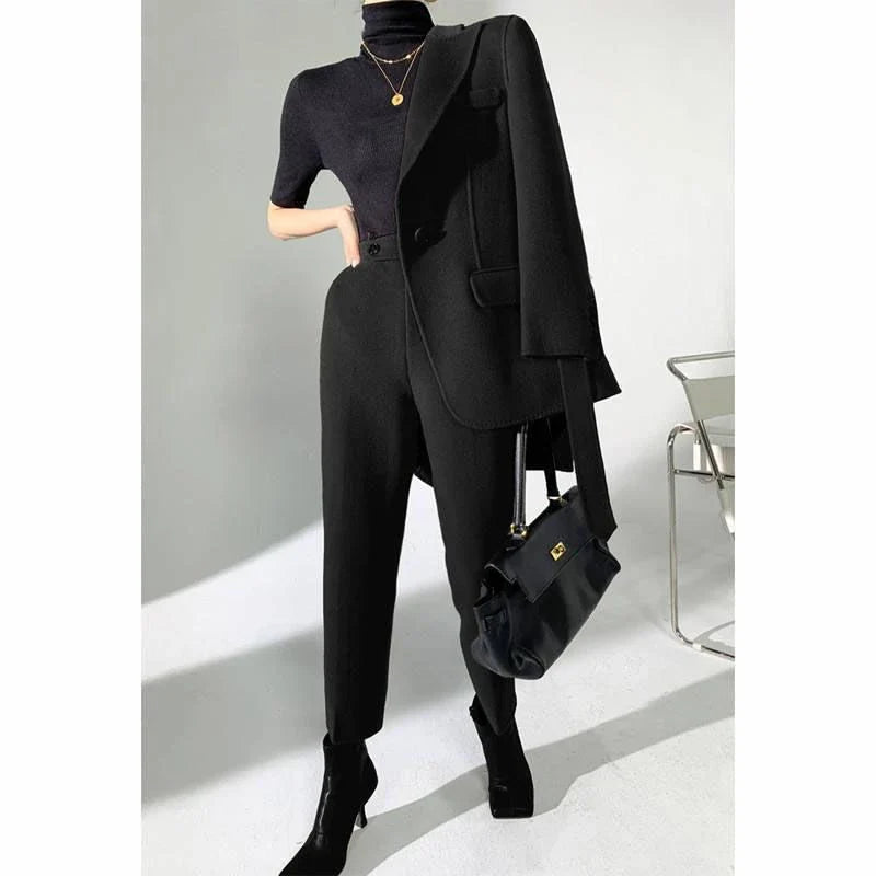 A chic and elegant woolen pant suit in black, featuring a belted jacket and warm trousers perfect for the autumn-winter season.