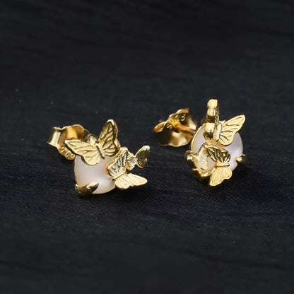 Close-up of a pair of 925 silver butterfly ear studs with gold plating, showing detailed animal zodiac modelling.
