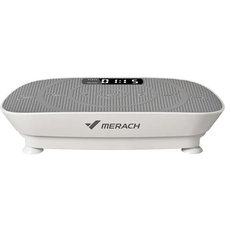 Grey portable vibration plate on a wooden floor, showing its slim 16cm profile and textured platform surface.