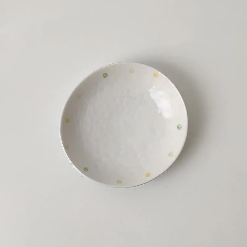 Japanese-style dot pattern porcelain plates and bowls in irregular oval and round shapes on a table.
