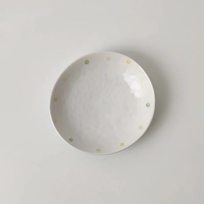 Japanese-style dot pattern porcelain plates and bowls in irregular oval and round shapes on a table.