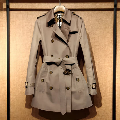 Khaki women's double-breasted trench coat with flight sleeves on a hanger.