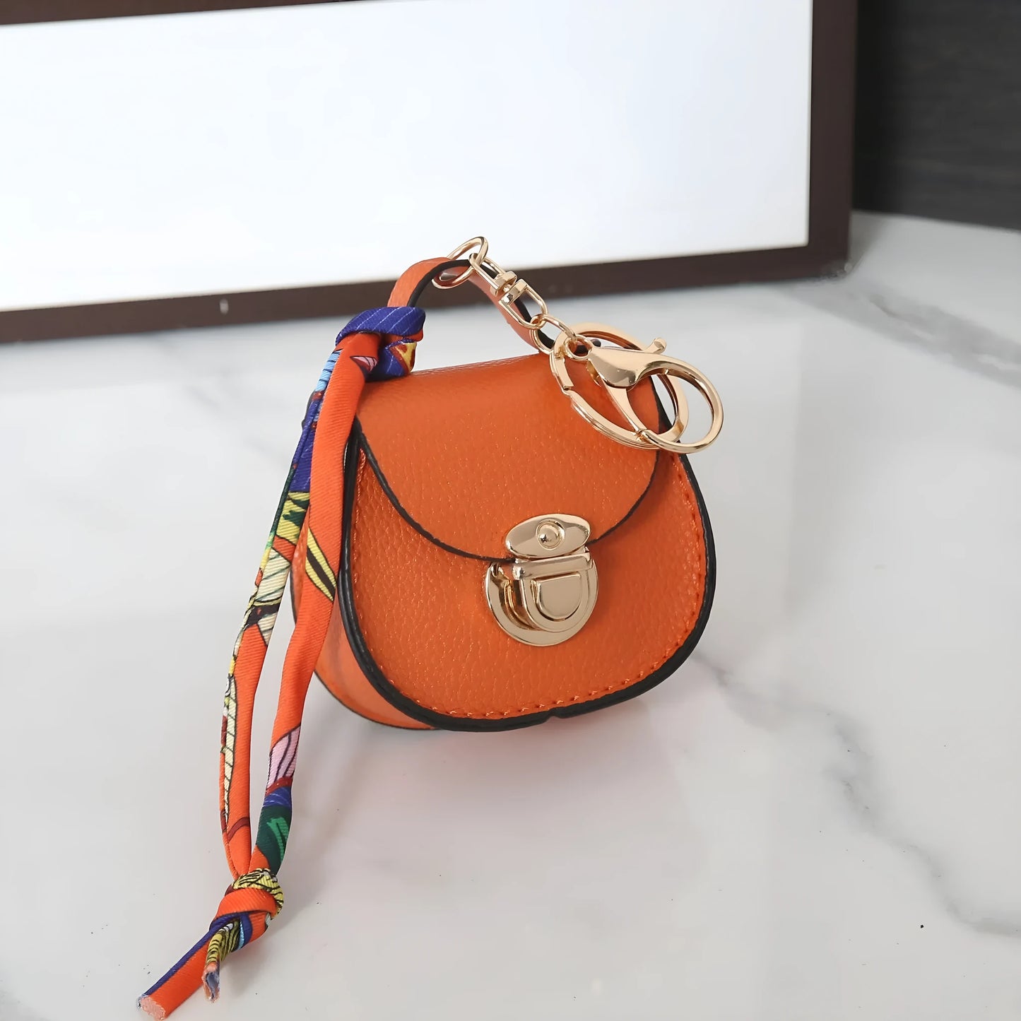 Solid colour PVC coin purse keychain shown in saddle bag black, orange, brown, red, grey, and pink.