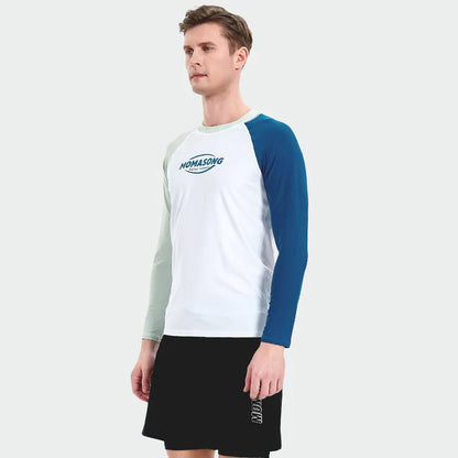 Man wearing a white long-sleeved swim top and matching blue swim trunks at the beach.