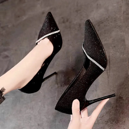 Gold women's stiletto high heels with pointed toe on a plain background.
