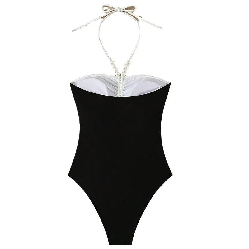 Women's black and white one-piece swimsuit with pearl spaghetti straps and a slimming silhouette.