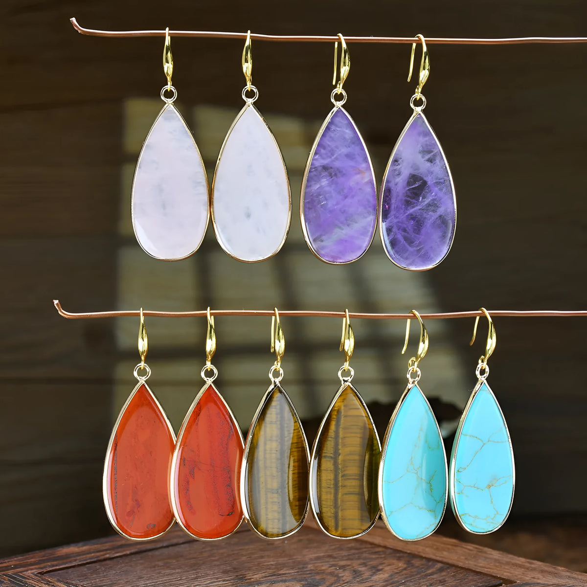 Handmade vintage long water drop earrings with tigereye stone and sterling silver hooks on a textured background.