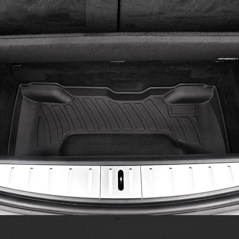 Custom black rubber floor mats with textured surface and TPE driver's footrest, fitted in a Tesla interior.