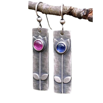 A pair of antique-finish geometric earrings with a red sapphire stone in an elliptical silver-tone setting.