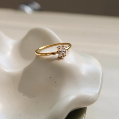 A gold-coloured stainless steel ring in a heart shape and an oval shape on a simple band.