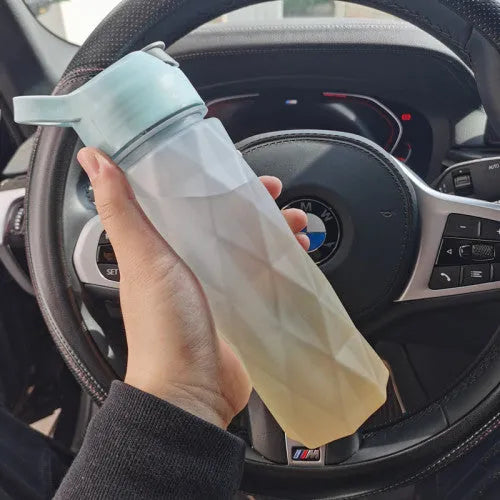 White spray water bottle with black leakproof lid and handle strap on a table