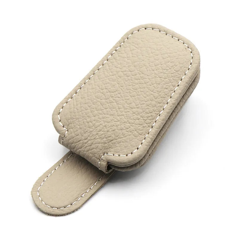 Car sunglasses holder clip with PU leather case attached to a sun visor.