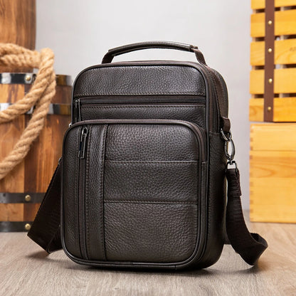 Vertical black genuine cowhide leather shoulder bag with a zip opening and soft handle, shown with internal organiser pockets.