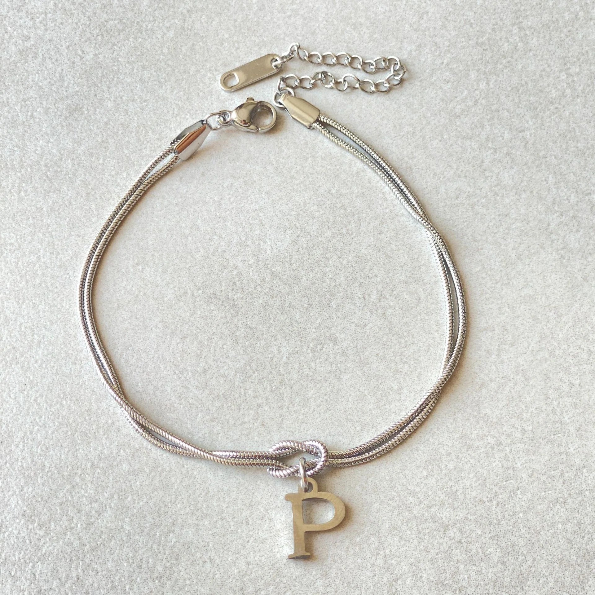 Elegant letter charm bracelets for women in gold and silver tones, featuring a delicate snake chain design and personalised letter charms.